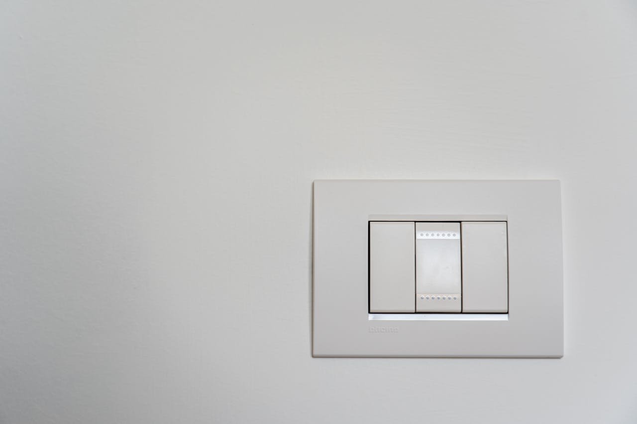 Close-up of a modern white light switch on a clean wall.